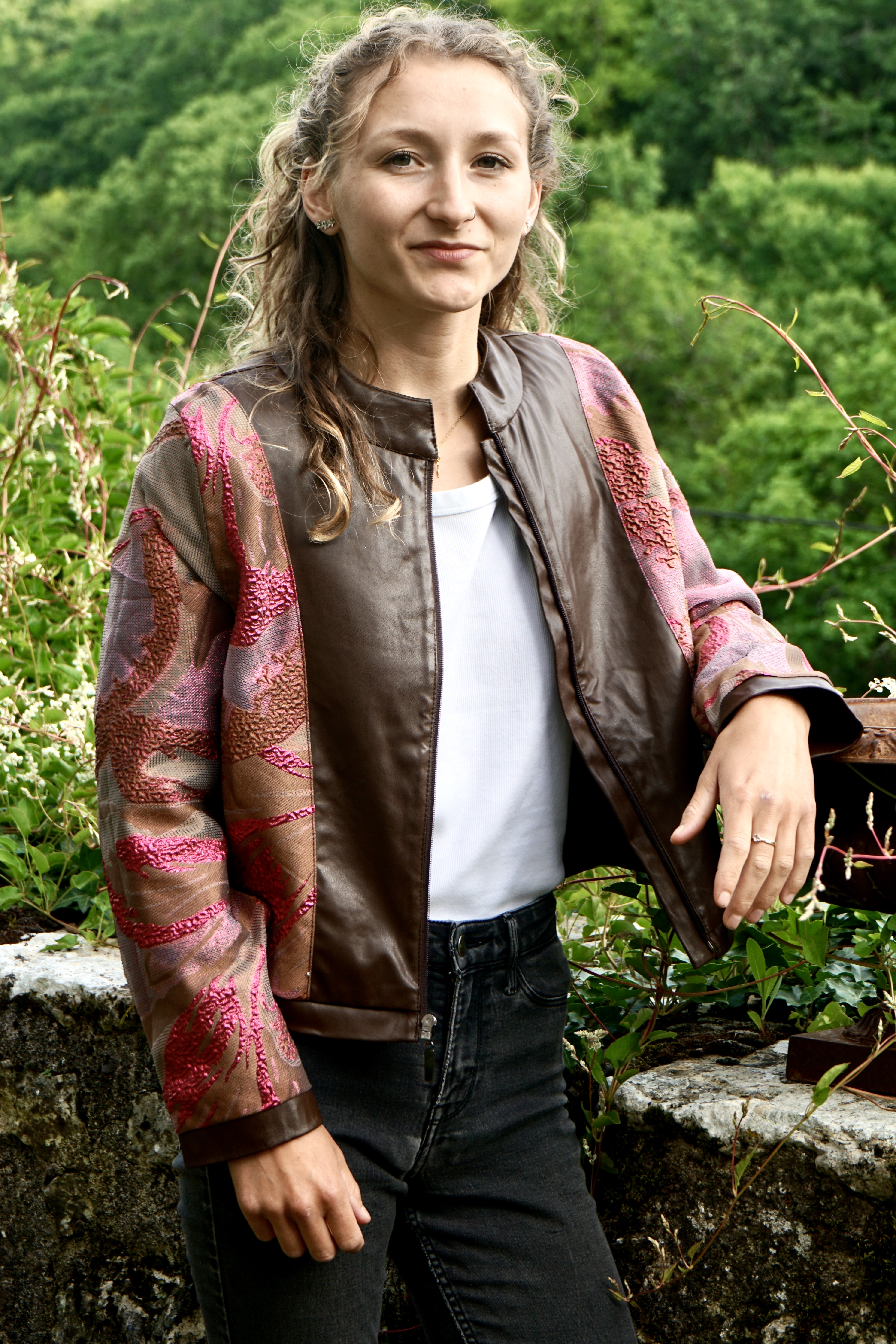Model wearing luxury bespoke vegan leather jacket in chestnut brown   showing  the red flame lining and the quality of craftsmanship